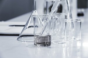 Glass beakers and flasks of colored liquid on a chemistry lab bench