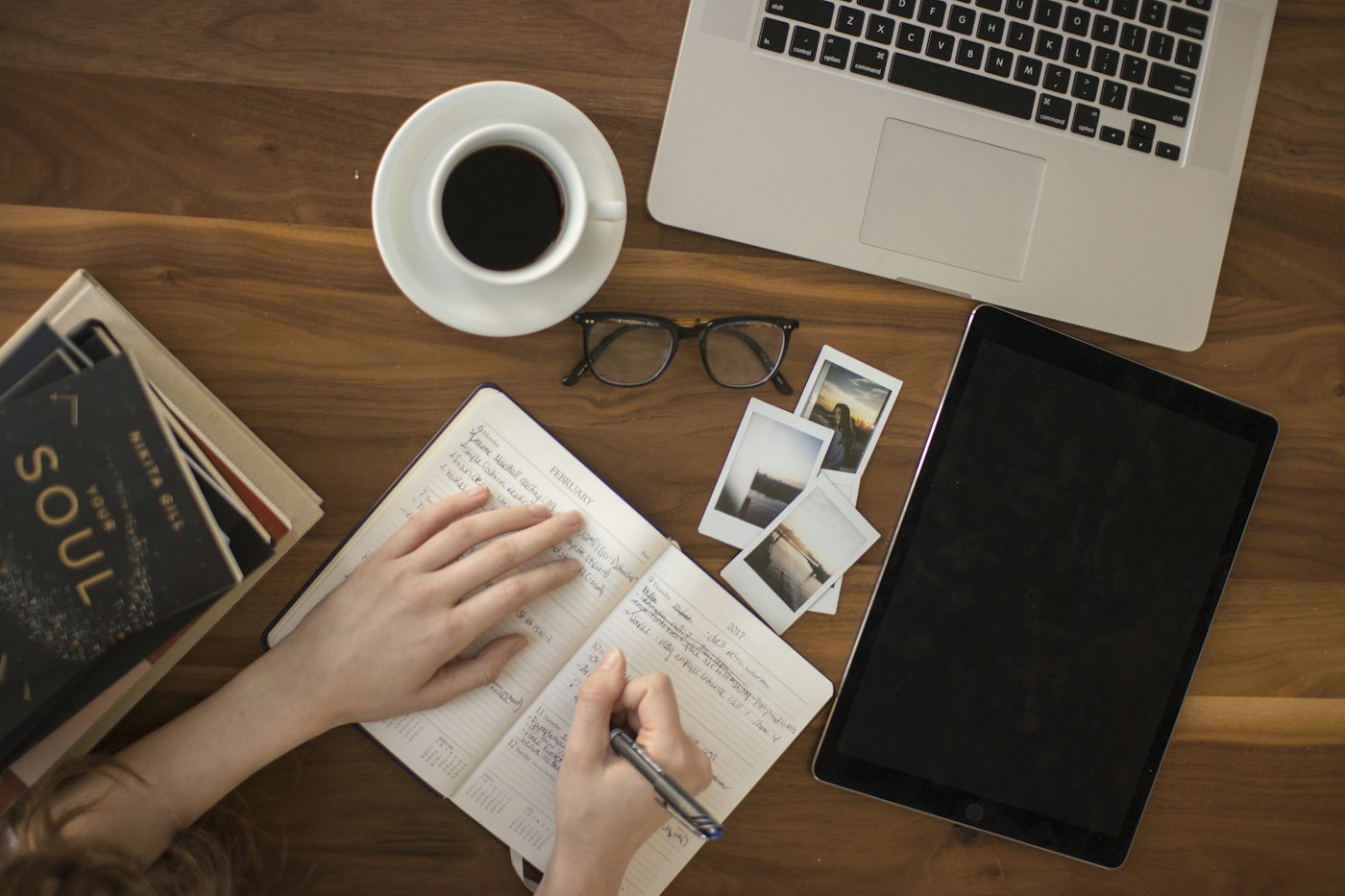 Coffee cup, open notebook, and laptop on a wooden desk