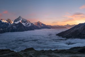 A mountain peak rising above a layer of clouds